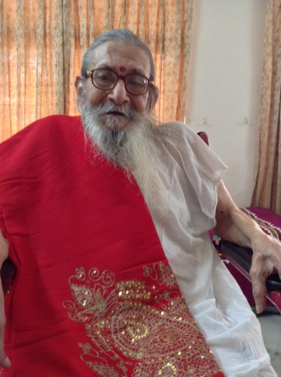 Pundit Purushottamshastri Phadke in old age, in spectacles and a red shawl, his beard long and white.